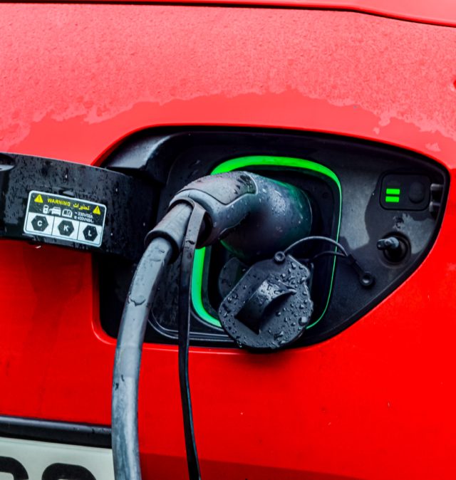 A red car is plugged into an electric charger.