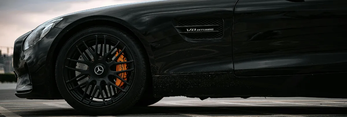 Close-up side view of a black Mercedes-Benz sports car, featuring the front wheel, orange brake caliper, and V8 Biturbo badge—an unmistakable icon, expertly maintained through professional Mercedes-Benz Servicing.