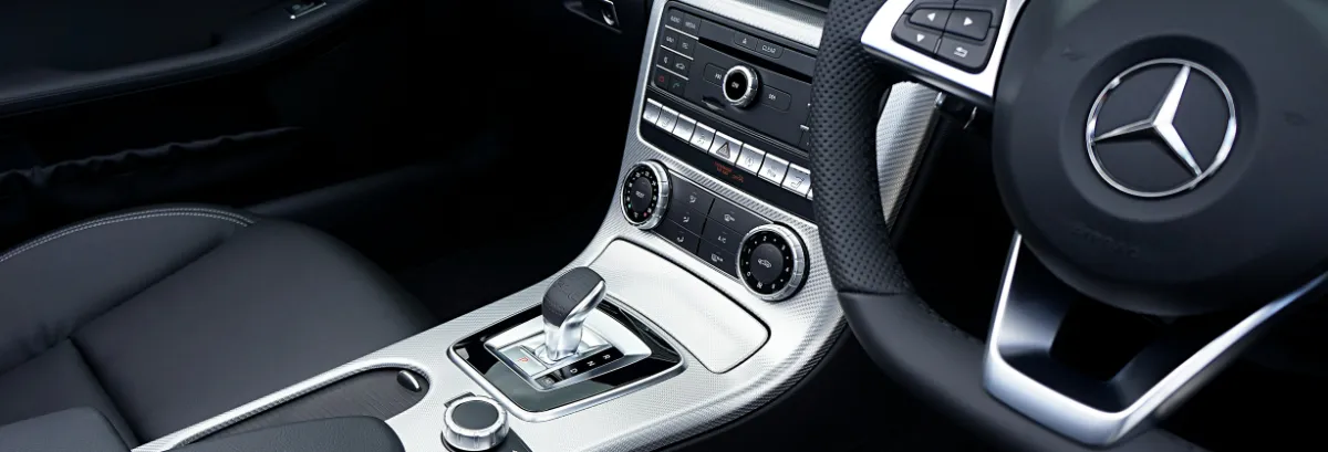 Close-up view of a Mercedes-Benz car interior showing the steering wheel with logo, gear selector, control knobs, and dashboard—showcasing the premium quality you can expect from expert Mercedes-Benz Service or professional Mercedes-Benz Repair.